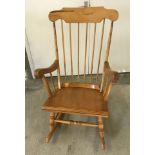 A vintage light wood rocking chair with spindle back and turned detail to legs.