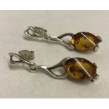 A pair of modern design silver and amber drop earring.