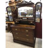 A vintage dark wood vanity chest with folding side mirrors.