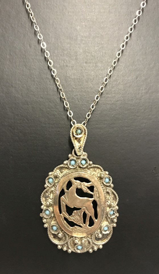 A 925 silver pendant of a leaping deer set with small turquoise stones on a silver chain.