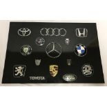 A mounted collection of car badges.