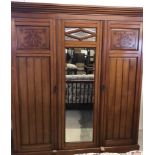 A vintage mahogany triple Gentleman's wardrobe with carved detail to doors and bevel edged mirrors.