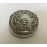 A small circular silver lidded trinket pot with scroll and bird design to top with blank cartouche.