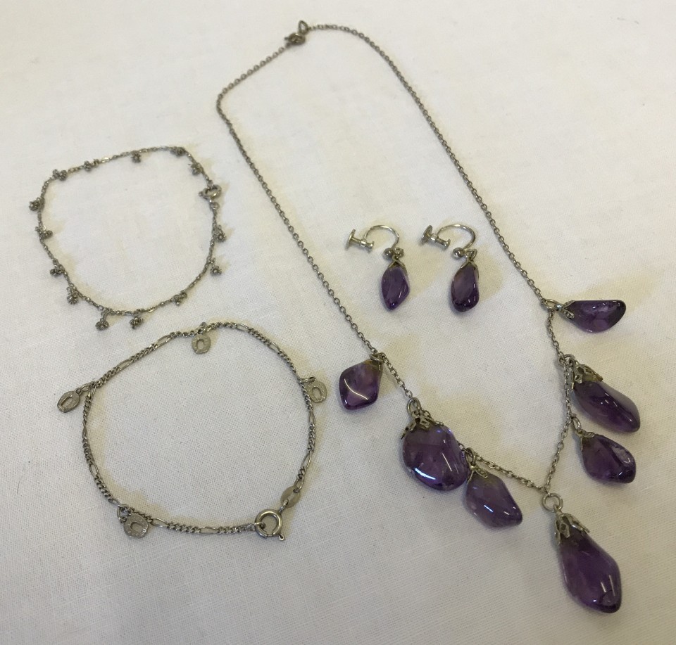 A silver necklace with 7 amethyst pendants and matching silver & amethyst earrings.