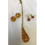 A large amber drop pendant on a goldtone chain.