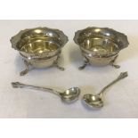 A matching pair of silver salts with claw feet and scalloped edge tops.