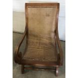 A vintage cane seated low easy chair with scroll design arms.