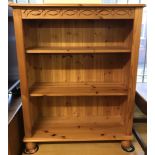 A modern pine bookcase with carved detail to front and bun feet.