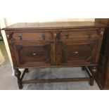 A dark oak vintage 2 door, 2 drawer side board with carved detail to front and legs.