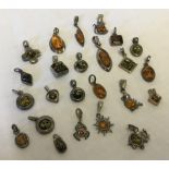 A collection of 24 silver/white metal pendants/charms all set with amber.