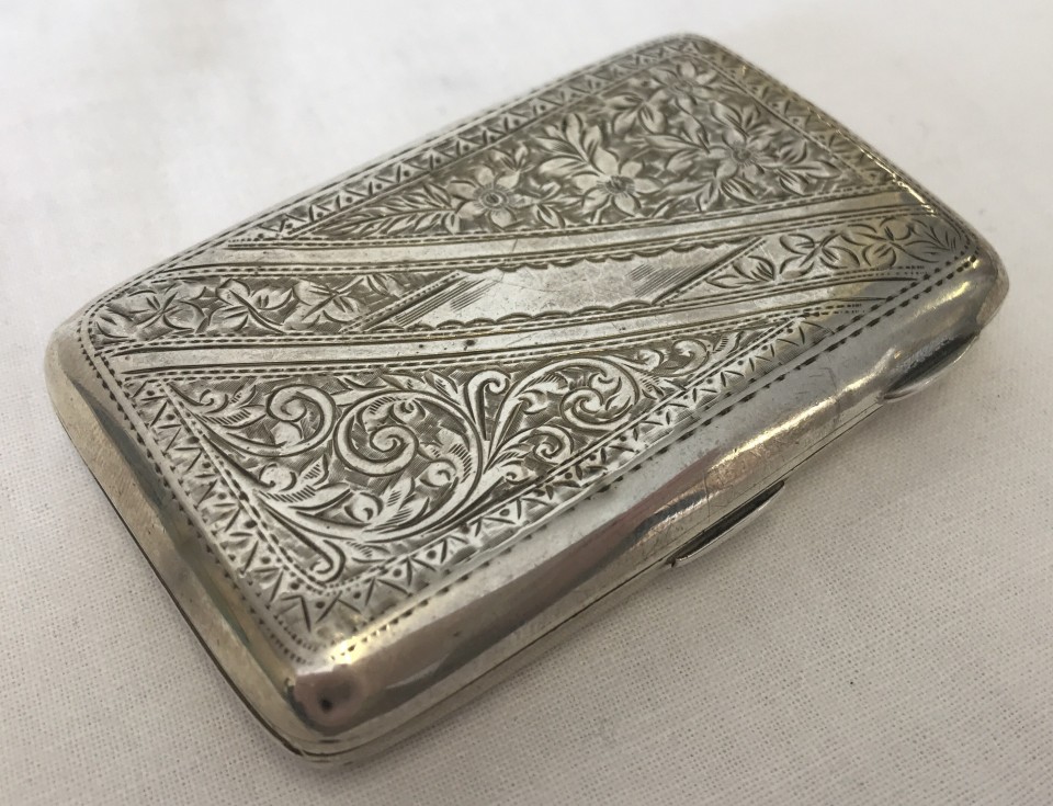 A small silver ladies cigarette case with engraved floral and scroll decoration to front and back.