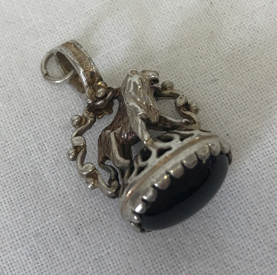 A small silver fob with lion detail to top, set with black onyx cabochon.