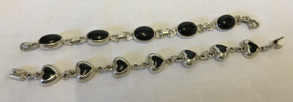 2 heavy silver bracelets, both set with black stones.