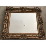 A large ornate gilt framed heavy wall hanging mirror.