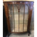 A vintage bow fronted display cabinet with glass door and side panels.