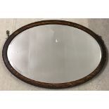 A vintage dark oak framed oval shaped wall hanging mirror.