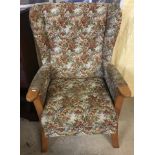 A vintage light wood wing back chair with floral tapestry style upholstery.