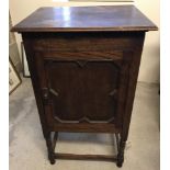 An Art Deco dark wood cupboard on turned legs with lift up lid.