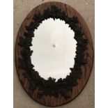 Oval mirror in oak frame with cast iron floral decoration.