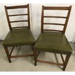 A pair of antique ladder back chairs with olive green studded leather upholstered seats.