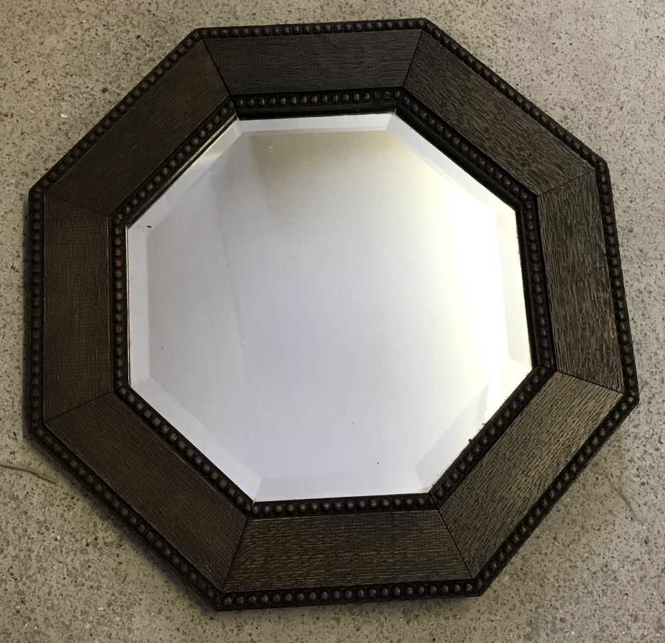 A small vintage octagonal dark oak framed wall hanging mirror.