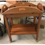 A modern medium wood butlers tray tea trolley with brass castors.