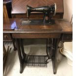 A vintage wooden framed Singer treadle sewing machine with lift up lid.