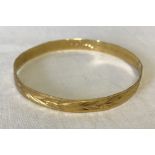 A 22ct gold bangle with engraved detail.
