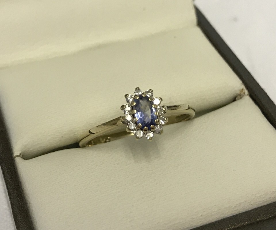 Pretty hallmarked 9ct gold ring set with oval sapphire surrounded by small diamonds.