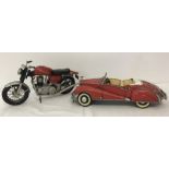 A vintage tin plate Norton motorcycle together with a Rolls Royce convertible, both in red colours.