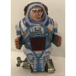Vintage tin plate wind up astronaut with spark panel and paddle feet.