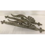 A pair of ornate metal wall brackets with fleur de lis decoration.