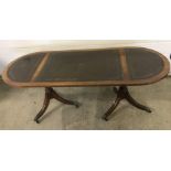 A reproduction oval topped coffee table on tripod pedestal legs.