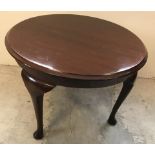 A small round dark wood coffee table with cabriole legs.