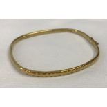 9ct gold bangle with safety clasp and decorative engraving to one side.