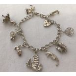 A ladies silver charm bracelet with padlock and safety chain and 9 charms.