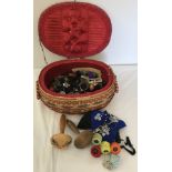 A vintage sewing basket decorated with flowers and contents.