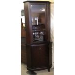 A Stag dark wood corner display cupboard with interior glass shelves and lighting.