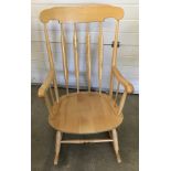 A vintage light wood rocking chair with turned detail to legs.
