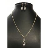 A silver pendant chain and earrings set with 'treble clef' design.
