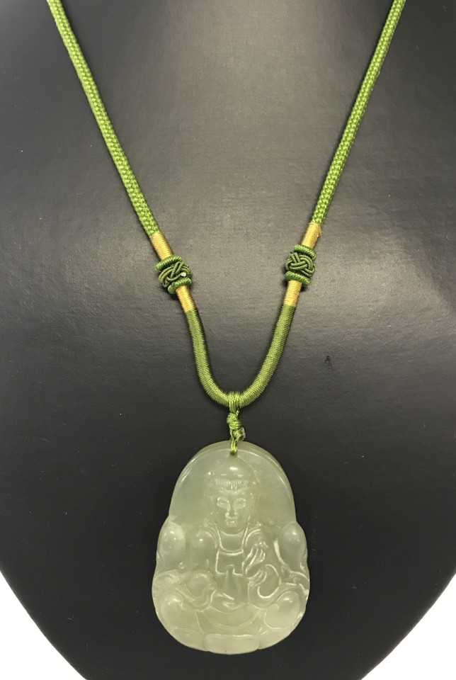 Carved jade Buddha pendant hanging on green cord.