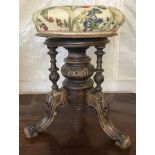 A decorative screw top stool with carved detail to pedestal and tripod feet and floral upholstery.