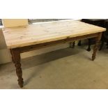 A modern solid pine kitchen table with natural wood top and turned legs.