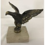 A brass eagle ornament mounted on a square marble base.