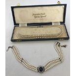 A boxed double string of Pompadour faux pearls with marcasite set clasp.
