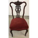 A Victorian bedroom chair with decoratively carved back, ceramic castors and velvet upholstered seat