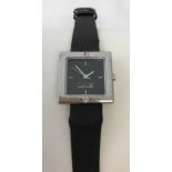 Black dial square stone set wristwatch on a satin finish strap.