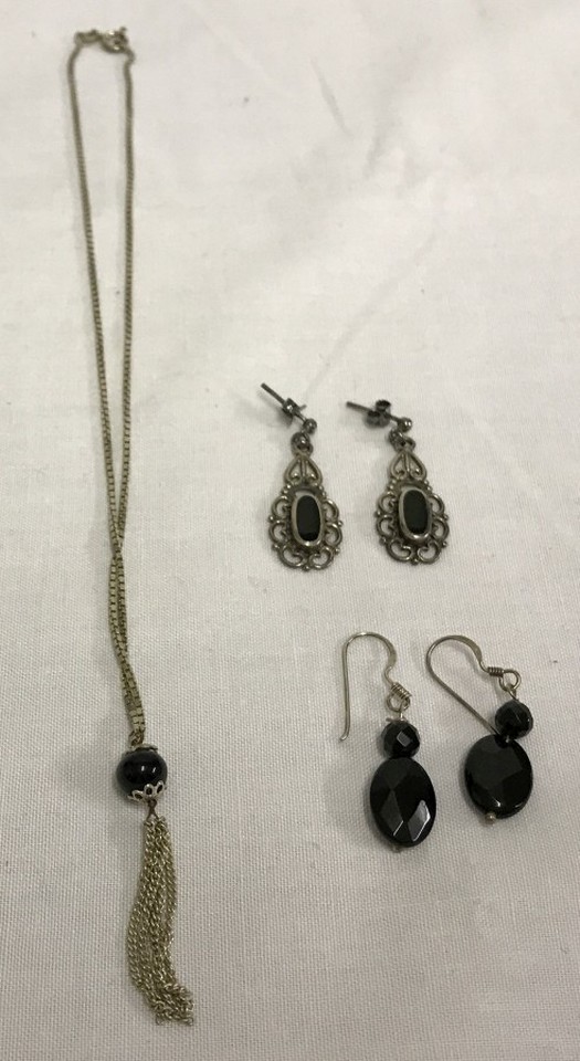 2 pairs of silver earrings together with a silver necklace, all set with black stones.