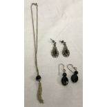 2 pairs of silver earrings together with a silver necklace, all set with black stones.