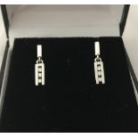 A pair of 18ct white gold 3 diamond drop, round cut, channel set stud earrings.